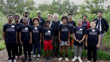 MBK participants posing with Mayor Dyer in front of a community garden