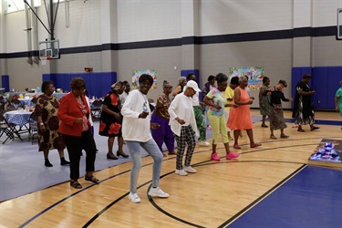 Residents dancing in a gymnasium at an event at a neighborhood center 