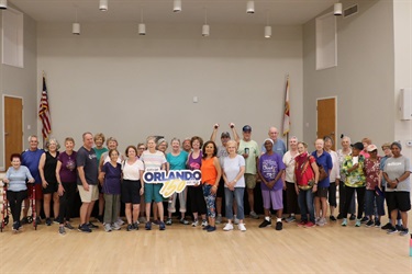 A group of residents posing at a neighborhood center holding a sign commemorating the city's 150th anniversary