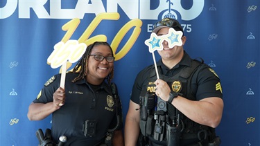 Two OPD Officers posing in front of an Orlando 150 backdrop.