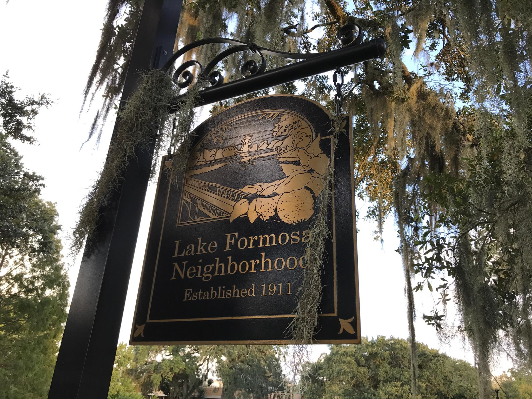 Lake Formosa Neighborhood sign hanging on a post near greenery
